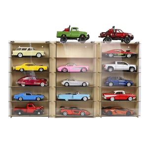 May include: A wooden display case with 15 slots for displaying toy cars. The case has three sections, each with five slots. The cars are a variety of colours, including red, blue, yellow, green, and black.