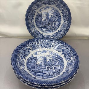 May include: A set of three blue and white ceramic bowls with a scalloped edge. The bowls feature a vintage design of a village with a church and houses.
