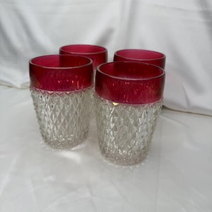 May include: Set of four clear glass tumblers with a diamond pattern and a red rim.