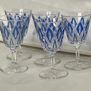 Puede incluir: Juego de cinco vasos de cristal transparente con tallo y un patrón de diamantes azules.