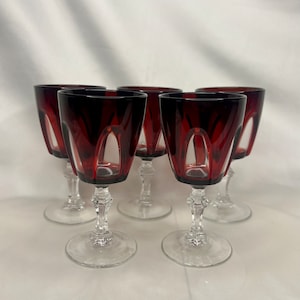 May include: Set of six red wine glasses with clear stems and bases. The glasses have a unique, faceted design.