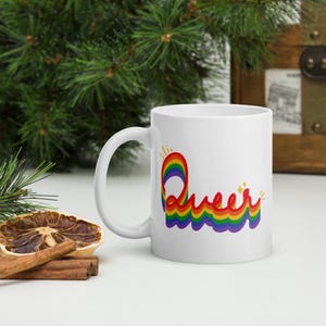May include: White ceramic mug with a rainbow design that spells out the word "Queer".