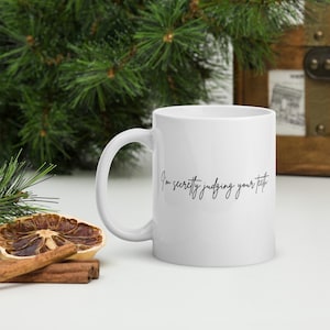 May include: White ceramic coffee mug with a black handwritten message that reads "I'm secretly judging your teeth".