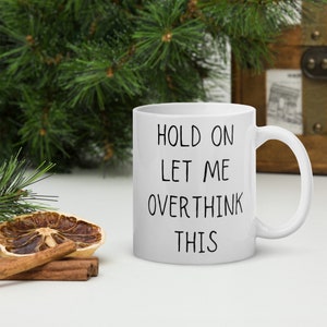 May include: White ceramic mug with black text that reads "Hold on let me overthink this".