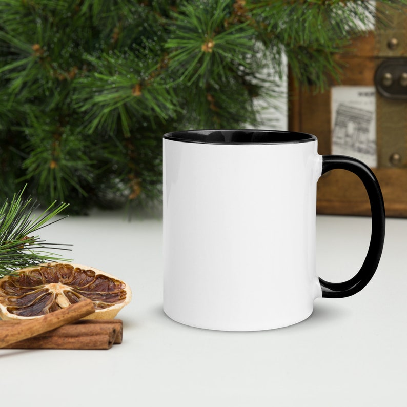 May include: A white ceramic mug with a black rim and handle. The mug is sitting on a white surface.