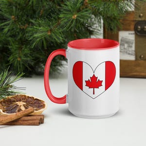Peut inclure: Une tasse en céramique blanche avec un intérieur et une poignée rouges. La tasse présente un cœur rouge avec un drapeau canadien blanc à l'intérieur. Le cœur a un contour blanc et le drapeau canadien a une feuille d'érable rouge.