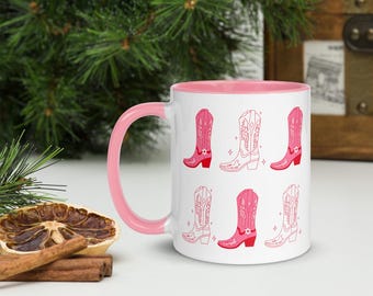 May include: White ceramic mug with a pink rim and handle. The mug features a repeating pattern of pink cowboy boots with white outlines.