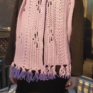 May include: A light purple crocheted scarf with a delicate pattern and fringe. The scarf is made with a soft yarn and has a lightweight feel.
