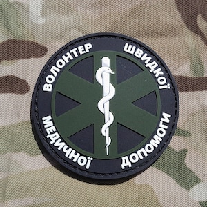 May include: Black and green embroidered patch with a white medical symbol and the text "Волонтер швидкої медичної допомоги" in white.