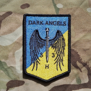 May include: A black and yellow embroidered patch with the text "DARK ANGELS" and a sword with wings.