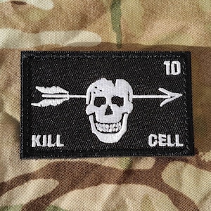 May include: Black patch with white embroidery of a skull with an arrow through it. The text "KILL CELL 10" is also embroidered in white.