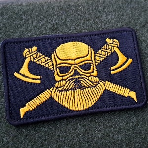 May include: A black patch with a yellow embroidered skull with a beard and crossed axes.