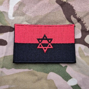 Könnte beinhalten: Roter und schwarzer gestickter Aufnäher mit einem roten sechszackigen Stern in der Mitte.