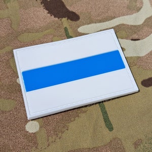 May include: A white patch with a blue stripe across the centre. The patch is made of a textured material and has a stitched border.