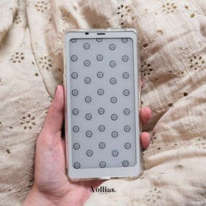 May include: A white phone case with a clear back and a pattern of small circles on the screen. The case is held in a hand.