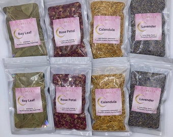 May include: A collection of eight clear plastic bags filled with various dried herbs and flowers, including bay leaf, rose petal, calendula, and lavender. Each bag has a pink label with the brand name "JAXBELLE" and the herb's name.