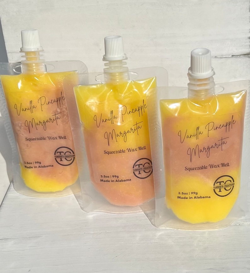 May include: Three pouches of yellow and peach-colored wax melts. The pouches are labeled "Vanilla Pineapple Margarita" and "Squeezable Wax Melt". The pouches are made in Alabama and are 3.5 oz (99g).