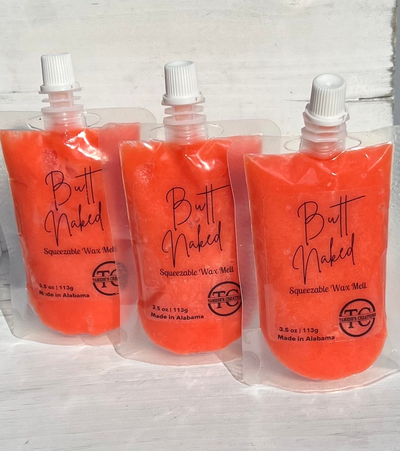 May include: Three orange squeeze pouches with the text "Butt Naked" and "Squeezable Wax Melt" on the front. Each pouch has a white cap and is labeled with "3.5 oz / 113g Made in Alabama".
