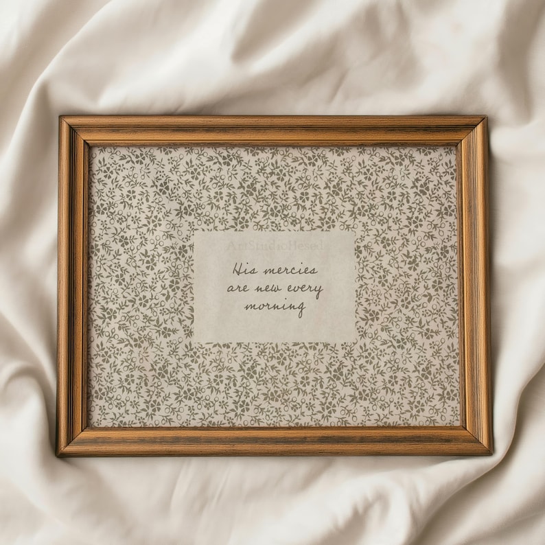 May include: A rectangular framed print with a floral patterned background and the text "His mercies are new every morning." The frame is a warm brown color, and the print is displayed on a white surface.