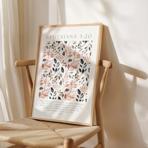 Puede incluir: Lámina artística enmarcada con un diseño botánico de hojas rosas, azules y doradas. El texto "EPHESIANS 3:20" está en la parte superior, con un versículo bíblico debajo. La impresión está enmarcada en un marco de madera clara.