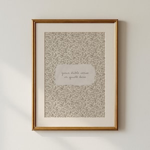 May include: A framed print with a gold-colored frame. The print features a floral pattern in shades of gray and beige. A light-colored, torn-paper-shaped area in the center contains the text "your bible verse or quote here."