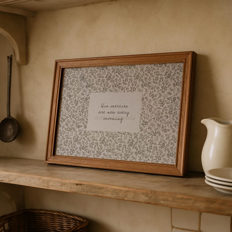 May include: A framed print with a light brown wooden frame. The print features a floral pattern in shades of gray and white, with the text "His mercies are new every morning."