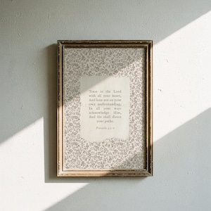 May include: A rectangular framed wall art piece featuring a light gray floral pattern background with a central off-white paper insert. The text reads: Trust in the Lord with all your heart, And lean not on your own understanding; In all your ways acknowledge Him, And He shall direct your paths. Proverbs 3:5-6.