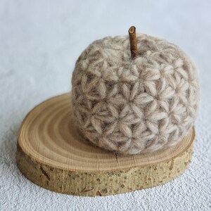 a textured pumpkin sitting on a slab of wood. The pumpkin is beige and crocheted with the Jasmine Stitch. The listing is for the pattern you need to make this modern fall decor