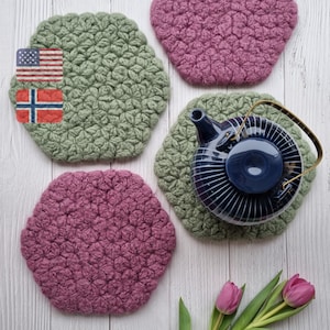 May include: Four crocheted pot holders in green and pink with a blue teapot on top of one of the pot holders. The pot holders are made with a star stitch pattern.