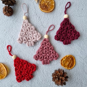 Puede incluir: Cinco adornos de &aacute;rbol de Navidad de ganchillo en rosa, rojo y burdeos. Los adornos cuelgan de cuentas de madera.