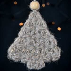 Puede incluir: Un adorno de &aacute;rbol de Navidad de ganchillo gris y dorado con una cuenta de madera en la parte superior.