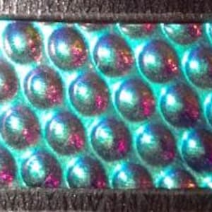 May include: A rectangular, iridescent material with a bubble-like pattern. The material has a rainbow sheen, with areas of blue, green, and purple. The text "96 C.O.E. RADI... RAINBOW" is visible on a white label. A white circle with the number "1" is on the right.