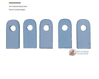 May include: Five light blue, rectangular precut fusing hangers with a circular hole at the top. The hangers are arranged in a row. The text "Em's Stained Glass Items" and "Precut Fusing Hangers" is visible.