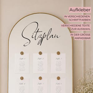 Könnte beinhalten: Eine Hochzeits-Sitzordnung mit goldenem Rahmen und cremefarbenem Hintergrund. Das Wort "Sitzplan" ist in eleganter schwarzer Schrift geschrieben. Sechs Karten sind mit goldenen Siegeln befestigt, jede mit Tischnummer und Gästenamen. Text "Aufkleber".