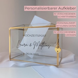 Könnte beinhalten: Eine transparente Hochzeitskartenbox aus Glas mit goldenen Verzierungen, einem herzförmigen Schloss und einer weißen Karte im Inneren. Auf der Box stehen die Namen "Laura & Matthias" und das Datum "06.06.2025". Der Text über der Box lautet "Personalisierbarer Aufkleber".