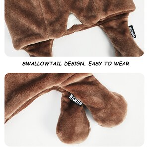 May include: A brown plush hat featuring a swallowtail design with two extended flaps. A small black fabric tag with the white text NANDN is attached to one of the flaps. The text SWALLOWTAIL DESIGN, EASY TO WEAR is printed between the two images.