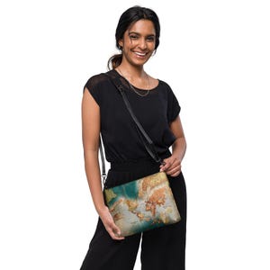May include: A woman is wearing a black top and black pants. She is carrying a crossbody bag with a world map design. The bag is made of leather and has a black strap.