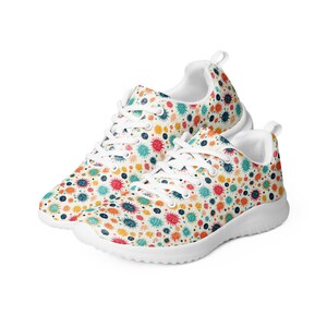 May include: White sneakers with a colorful abstract pattern of splattered paint. The pattern features red, orange, yellow, green, blue, and purple colors.