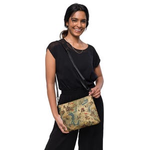 May include: A woman is wearing a black top and black pants. She is carrying a brown and blue crossbody bag with a map design. The bag has a black strap.