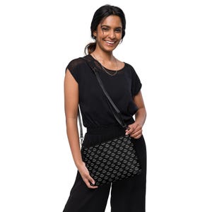 May include: A black crossbody bag with a white scale pattern. The bag has a long adjustable strap and a flap closure.