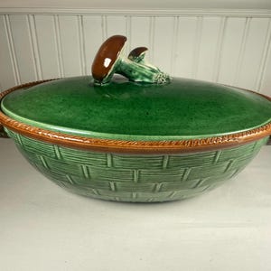 Peut inclure: Un plat de service en céramique verte avec un motif de panier tressé. Le couvercle est vert avec une poignée en forme de champignon marron. Le bord et les poignées sont marron. Une pièce décorative pour la cuisine.