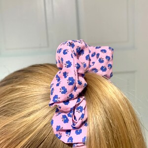 May include: A pink and blue floral patterned scrunchie for hair.