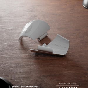 Puede incluir: Dos piezas de plástico blanco para impresión 3D. Las piezas tienen forma de soporte curvo y tienen una pequeña bisagra. El texto "MADE IN TAIWAN" está impreso en una de las piezas.