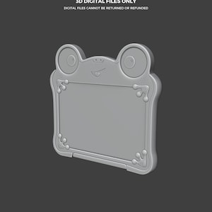 Puede incluir: Una tableta de dibujo digital gris con forma de rana. La tableta tiene una pantalla rectangular con esquinas redondeadas y elementos decorativos. El texto "THIS IS NOT A TOY" y "3D DIGITAL FILES ONLY" es visible. El logotipo de Abyssmo Workshop est&aacute; en la parte inferior.