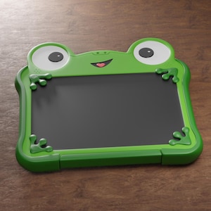 Op de afbeelding: Een groen, kikker-vormig tekentablet met een zwart scherm. De tablet heeft grote witte ogen met zwarte pupillen, een lachende mond en kleine kikkerpoten in elke hoek. De lijst is felgroen.