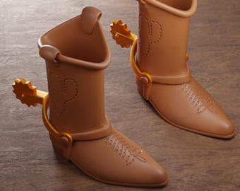 May include: Two brown cowboy boots with gold-colored spurs. Each boot features a cactus design and decorative stitching. The boots are set against a wooden background. The image also includes text that reads "Digital files for 3d printing" and "ABYSSMO WORKSHOP."