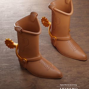 Puede incluir: Dos botas vaqueras de color marrón claro con espuelas doradas en los talones. Cada bota presenta un diseño de cactus cosido en la caña y un patrón decorativo en la punta. El texto en la parte inferior dice: Digital files for 3d printing ABYSSMO WORKSHOP.
