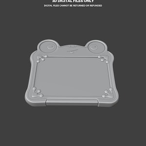 Puede incluir: Dise&ntilde;o de archivo digital gris con forma de rana. El dise&ntilde;o presenta una tableta rectangular con esquinas redondeadas y elementos decorativos. El texto en la parte superior dice "THIS IS NOT A TOY" y "3D DIGITAL FILES ONLY". El texto inferior dice "DIGITAL FILES CANNOT BE RETURNED OR REFUNDED".