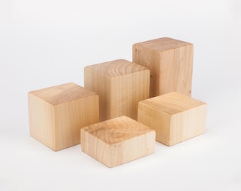 Puede incluir: Cinco bloques de madera de diferentes tamaños apilados en forma de escalera. Los bloques son de madera natural y tienen un color marrón claro.