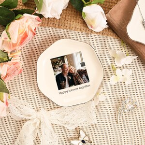 Puede incluir: Un plato de cer&aacute;mica de color crema, de forma irregular, con un borde negro. El plato presenta una fotograf&iacute;a de una pareja y el texto "Happy forever together". El plato est&aacute; rodeado de flores y objetos decorativos.